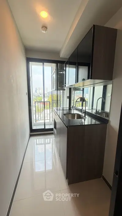 Modern kitchen with sleek cabinetry and city view from large window.