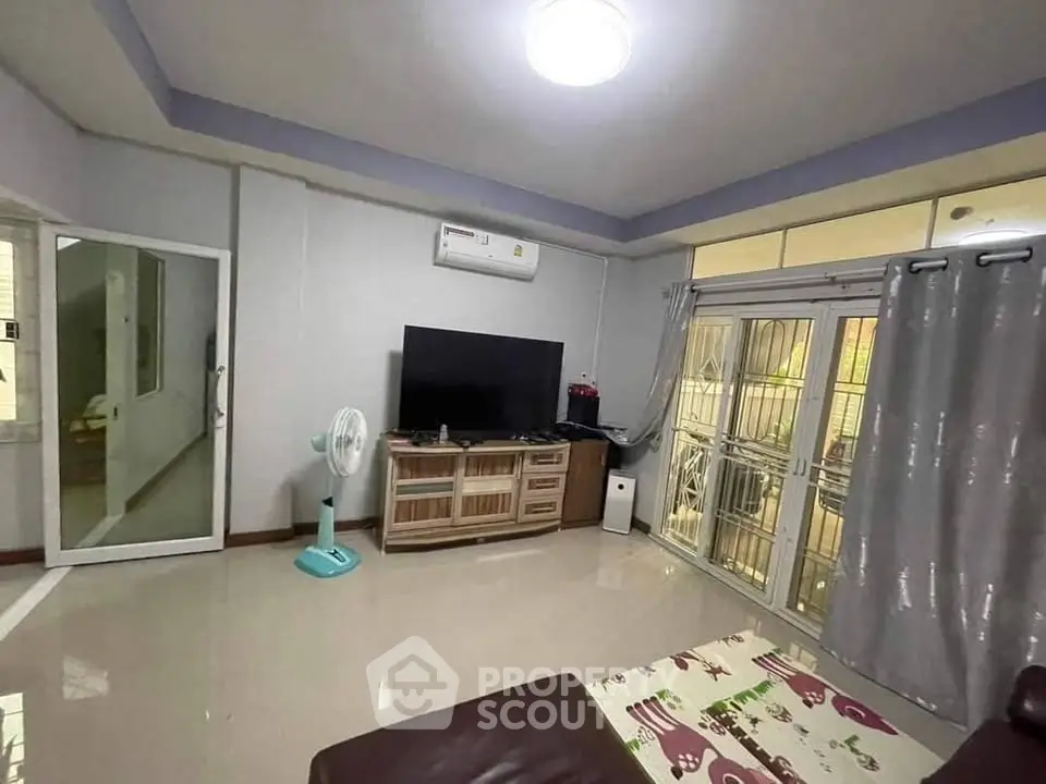 Spacious living room with modern TV setup and large windows