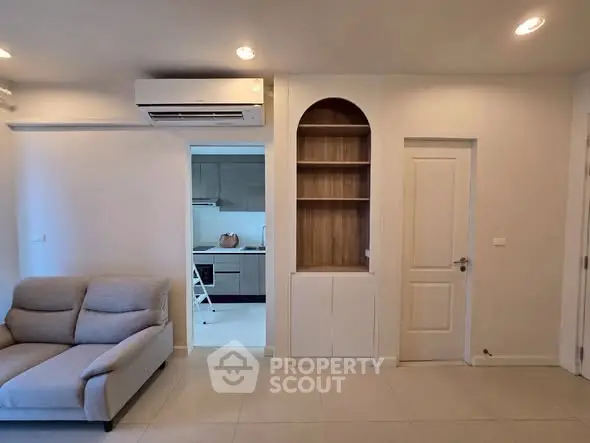 Modern living room with built-in shelving and view into sleek kitchen