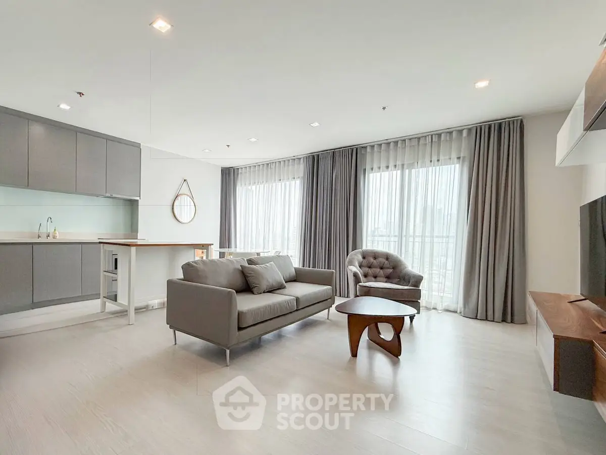 Spacious modern living room with elegant furniture and large windows offering natural light.