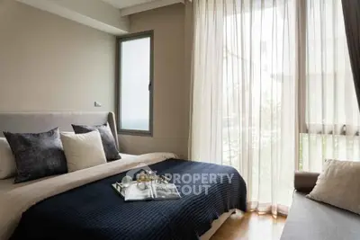 Cozy bedroom with elegant decor and natural light through sheer curtains.