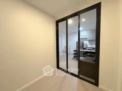 Modern apartment interior with sliding glass doors and open kitchen layout.