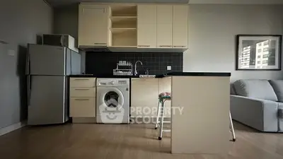 Modern kitchen with washing machine and sleek cabinetry in open layout apartment.