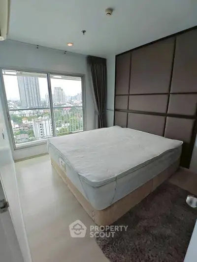 Modern bedroom with city view and large window in high-rise apartment