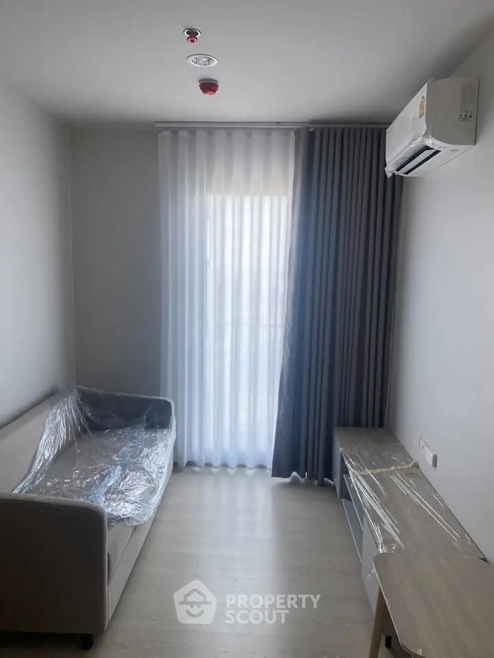 Modern living room with air conditioning and natural light, featuring a sofa and sleek furniture.
