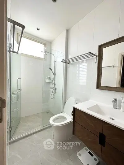 Modern bathroom with glass shower, sleek vanity, and natural light.
