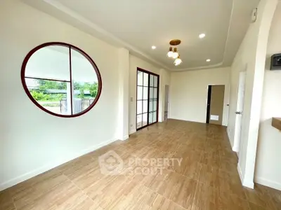 Spacious modern living room with unique circular window and elegant lighting