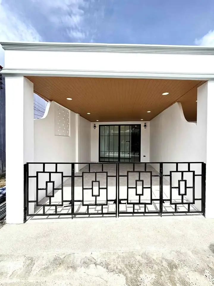 Modern house exterior with stylish geometric railing and spacious patio under a wooden ceiling.