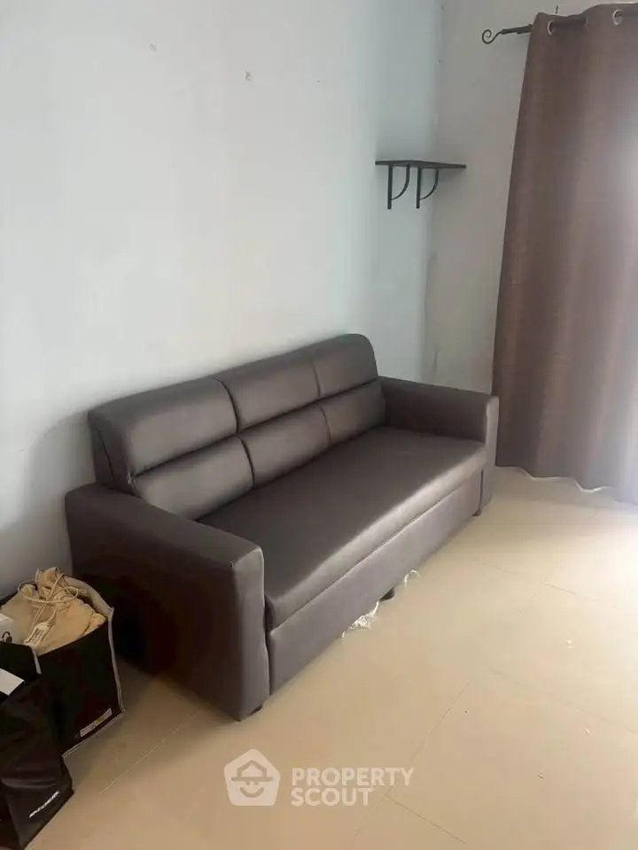 Cozy living room with modern sofa and natural light, perfect for relaxation.