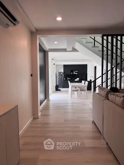 Spacious modern living room with open layout leading to a stylish kitchen and dining area, featuring sleek design and ample natural light.