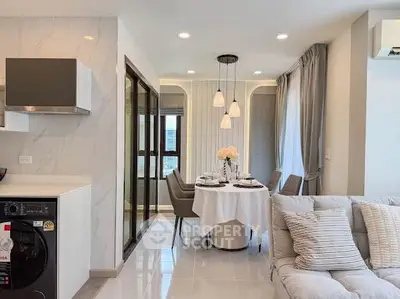 Modern open-plan living room with dining area and stylish kitchen, featuring elegant lighting and cozy seating.