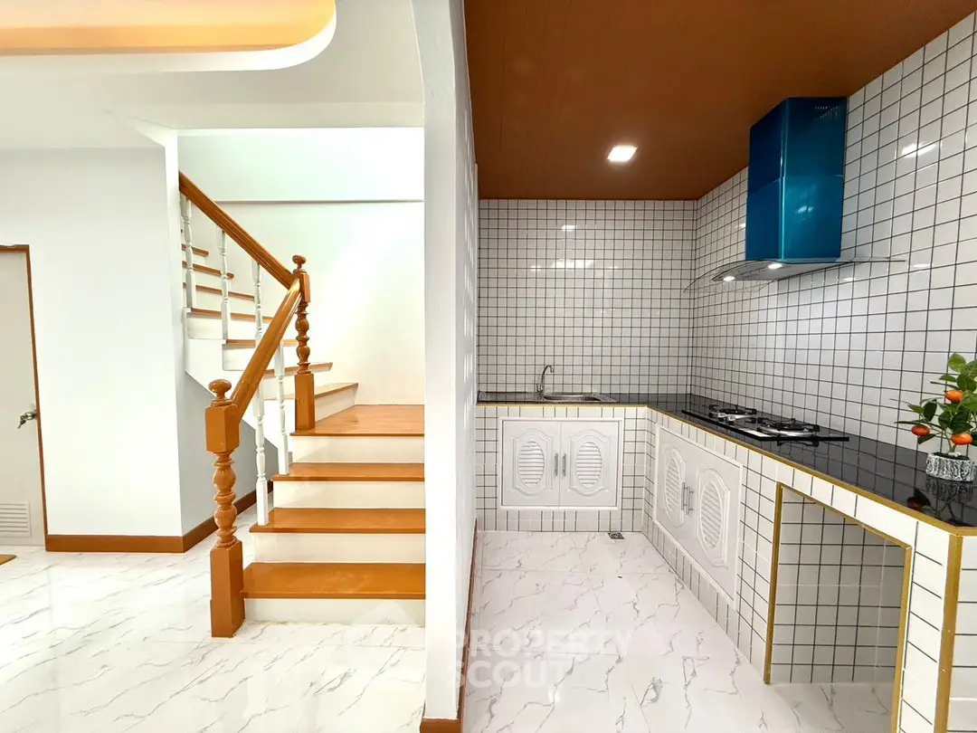 Modern kitchen with sleek design and adjacent wooden staircase