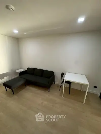 Modern minimalist living room with sleek black sofa and compact dining area.