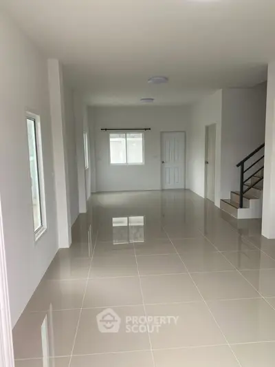 Spacious open-plan living area with tiled flooring and staircase