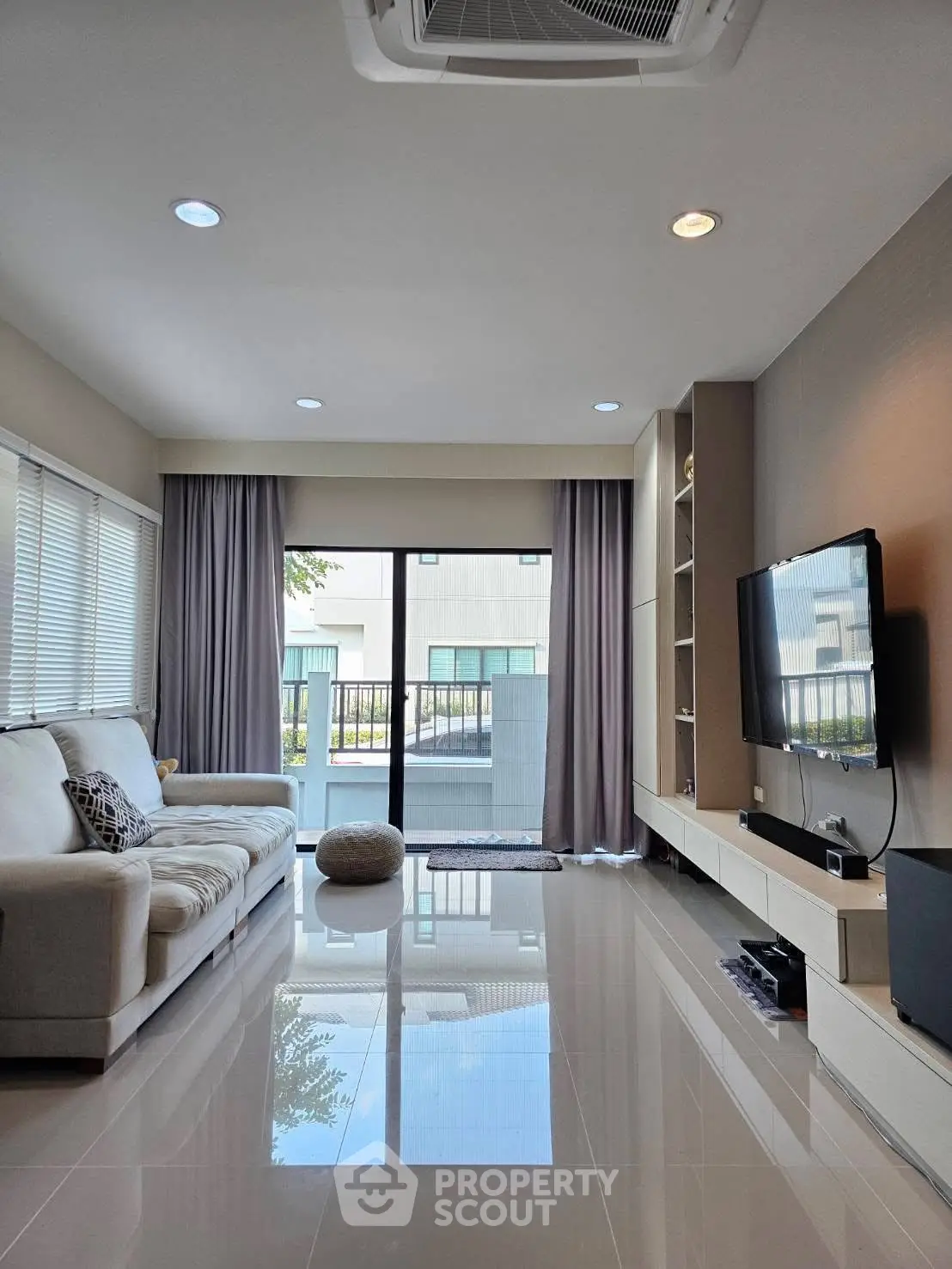 Modern living room with sleek design, large windows, and wall-mounted TV in a stylish home.