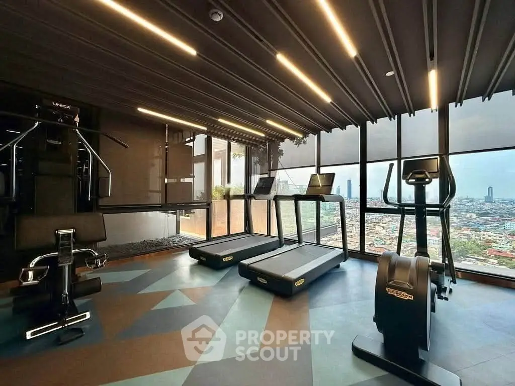 Luxurious gym with panoramic city views and modern fitness equipment in high-rise building.