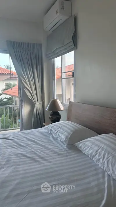 Cozy bedroom with natural light and balcony view in modern home.