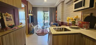 Chic modern living room with open kitchen, stylish decor, and natural light from large window.