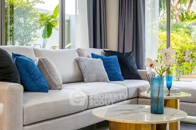 Luxurious living room with modern decor and large windows overlooking lush greenery.