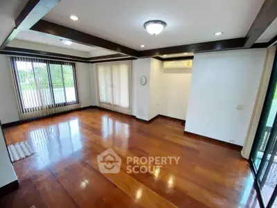 Spacious living room with wooden floors and large windows for natural light.