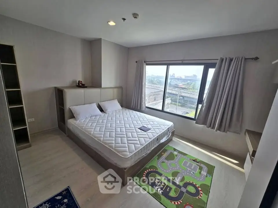Modern bedroom with large window and city view, featuring a comfortable bed and stylish decor.