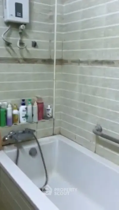 Cozy bathroom with bathtub and tiled walls, featuring essential toiletries for a comfortable experience.