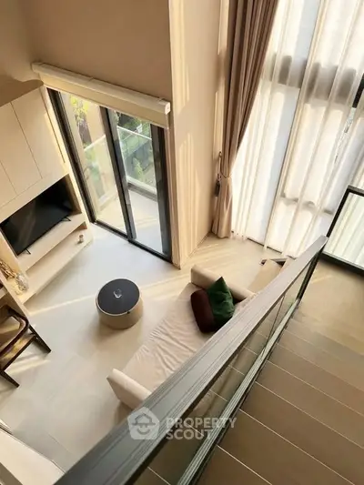 Modern living room with high ceilings and large windows offering natural light and a cozy seating area.