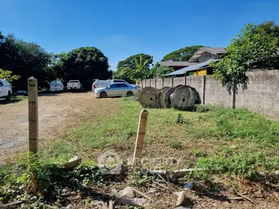 Spacious vacant lot with potential for development, featuring ample parking space and lush greenery.