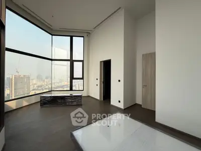 Spacious modern living room with floor-to-ceiling windows offering stunning city views.
