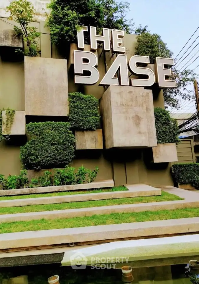 Modern architectural entrance with geometric design and lush greenery at The Base.