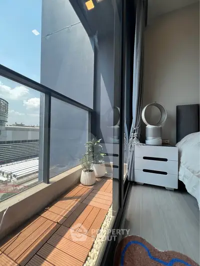 Modern bedroom with large window and city view, featuring stylish decor and natural light.