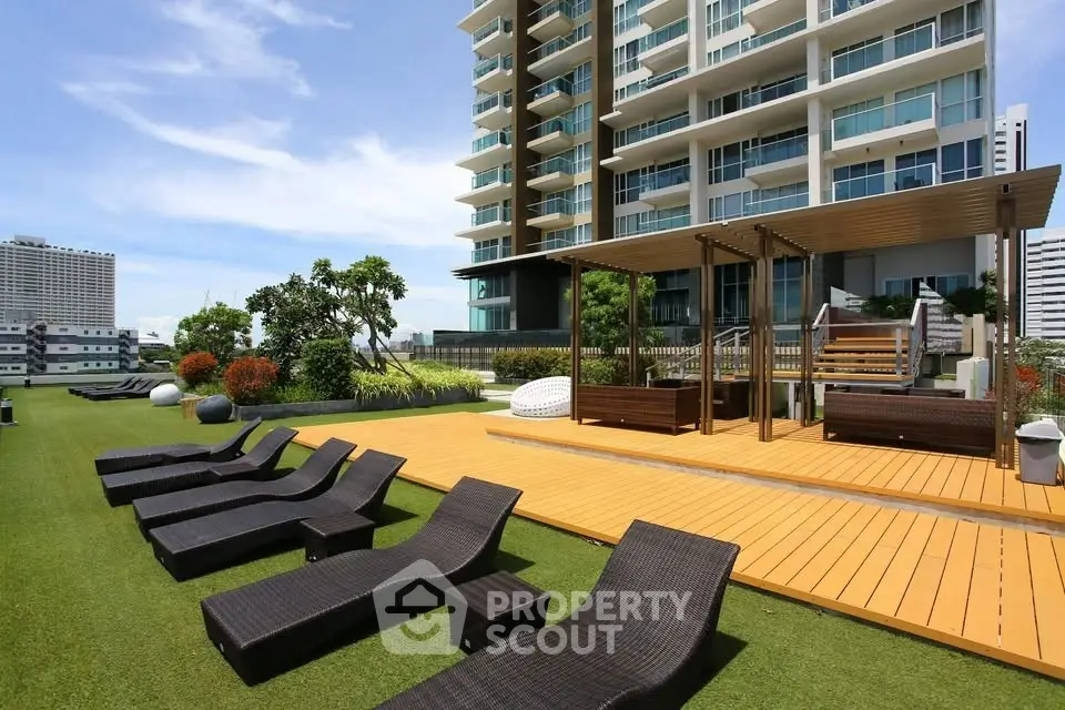 Luxurious rooftop terrace with modern lounge chairs and lush greenery in a high-rise building.