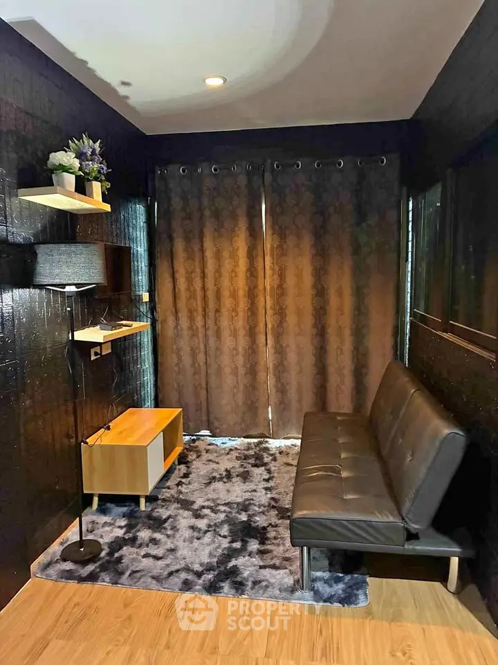 Cozy living room with modern black sofa, stylish decor, and elegant curtains for a chic urban vibe.