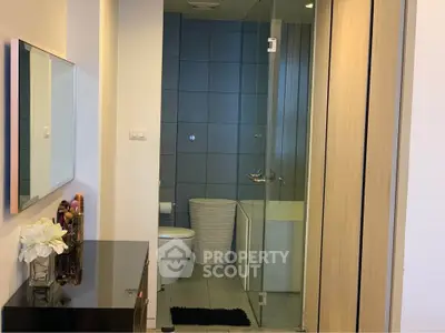 Modern bathroom with glass shower and sleek vanity in contemporary apartment.
