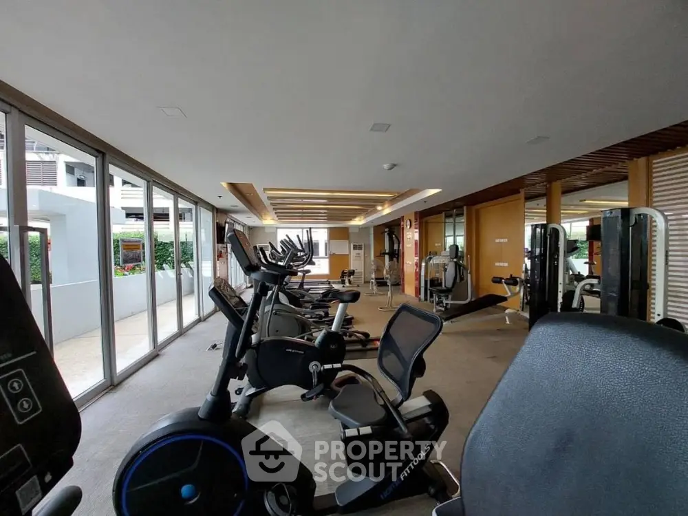 Spacious modern gym with state-of-the-art fitness equipment and large windows for natural light.