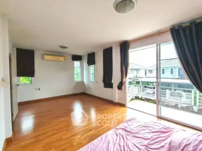 Spacious bedroom with wooden flooring and large windows offering ample natural light.