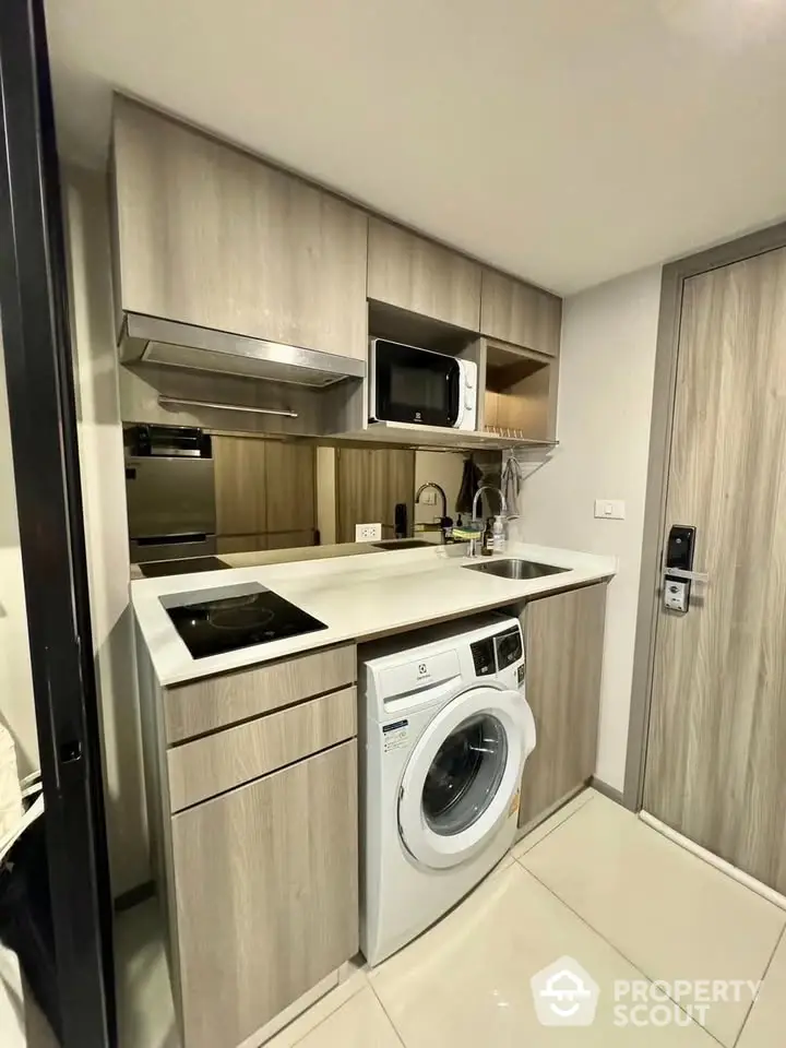 Modern compact kitchen with washing machine and microwave in stylish apartment