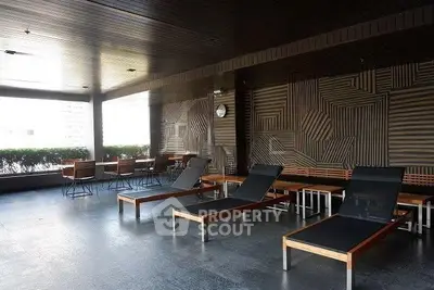 Modern building common area with stylish lounge chairs and dining tables, perfect for relaxation and socializing.