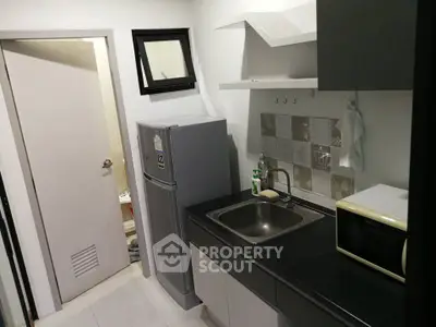 Compact modern kitchen with sleek cabinetry and stainless steel appliances in a cozy apartment.