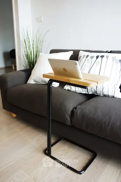 Modern living room with stylish sofa and sleek tablet stand, perfect for contemporary urban living.