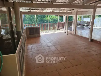 Spacious covered terrace with tiled flooring and garden view, perfect for outdoor relaxation.