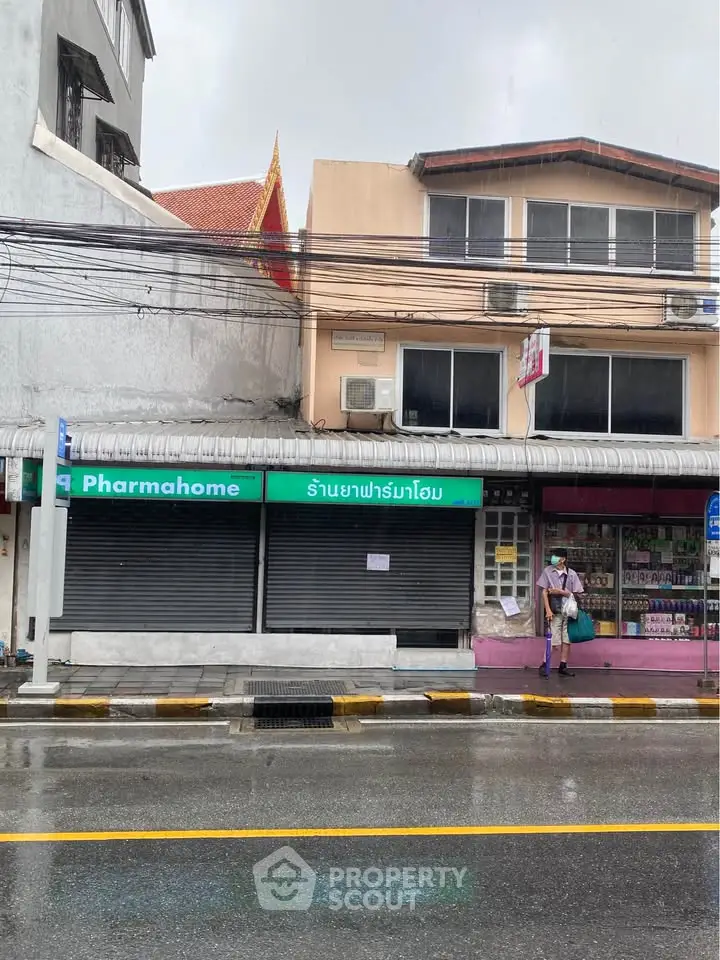 Street view of commercial building with pharmacy and residential units above, ideal for investment.