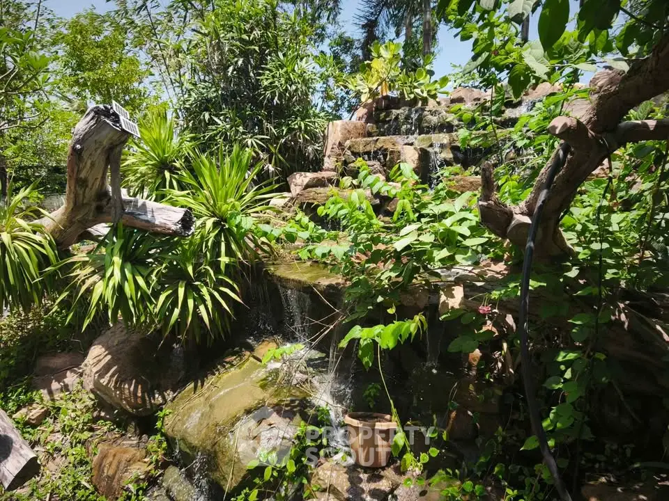 Lush garden with cascading waterfall and vibrant greenery, perfect for serene outdoor living.