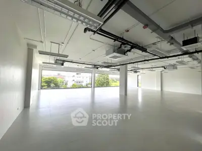 Spacious modern office space with large windows and open layout.