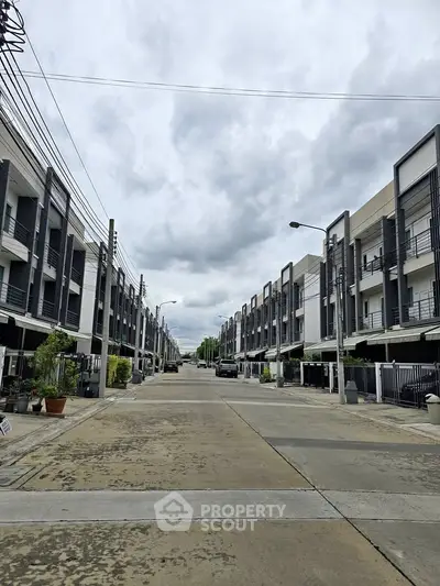 Modern townhouse complex with clean lines and spacious driveways under a cloudy sky.