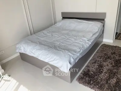 Modern bedroom with sleek bed and cozy rug in minimalist design.