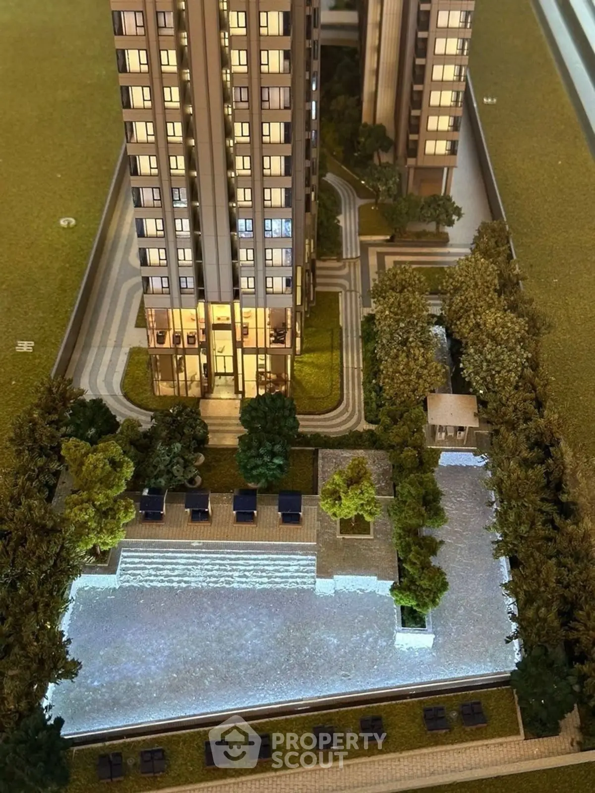 Stunning architectural model showcasing modern high-rise building with lush landscaping and elegant entrance.