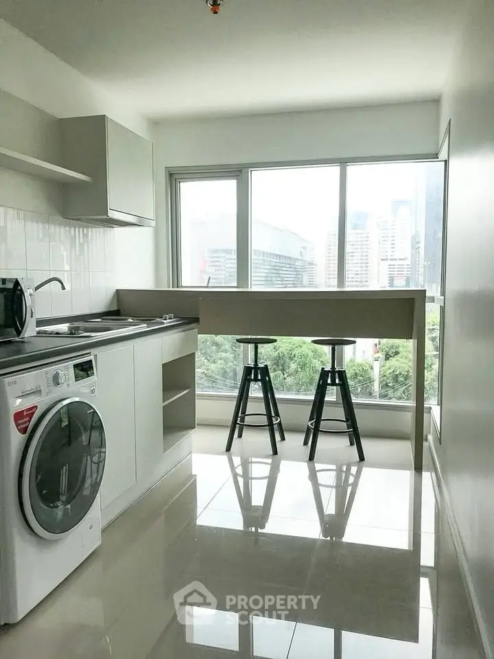 Modern kitchen with washing machine and city view, featuring sleek design and natural light.