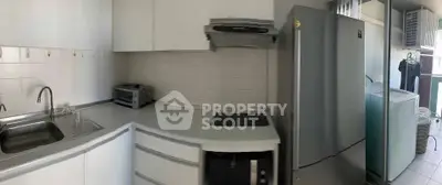 Modern kitchen with sleek appliances and ample counter space, featuring a fridge, oven, and washing machine.