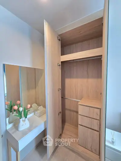 Spacious wooden wardrobe with built-in drawers and adjacent vanity in modern bedroom.